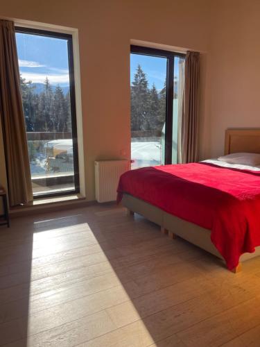 a bedroom with a red bed and a large window at Maisonette Mountain View - Euphoria Resort in Borovets