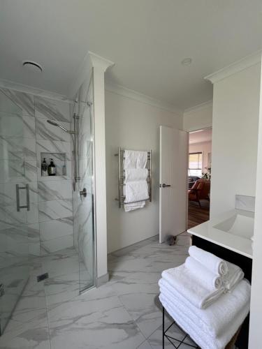 a bathroom with a shower and a sink with towels at Brand New 2-Bedroom Retreat in Quiet Cul-de-Sac in Hamilton
