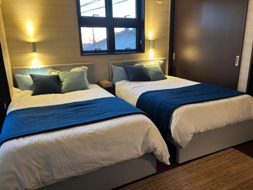 a bedroom with two beds with blue and white sheets at Cielito Hayama in Hayama