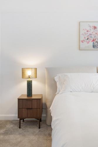 a bedroom with a bed and a table with a lamp at Pristine house near Dartford Station with Free Parking and Study in Dartford