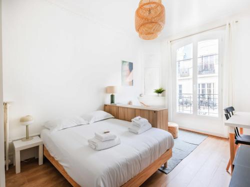 a white bedroom with a large bed with towels on it at Very attractive studio - 16ème - Mobility lease in Paris