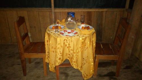 a table with a yellow table cloth and two chairs at Antares Jungle Lodge in Miraflores
