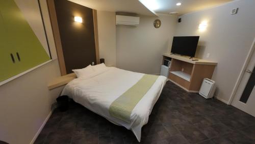 a hotel room with a bed and a television at ブルーエール in Nobeoka