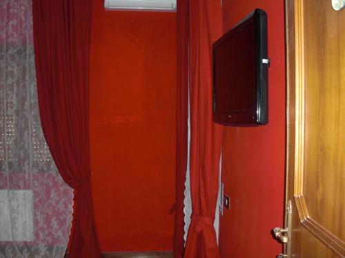 a room with red curtains and a flat screen tv at La Maison Blanche in Borghesiana 
