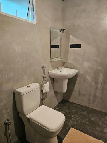 a bathroom with a white toilet and a sink at Muthu Hiriketiya in Dickwella