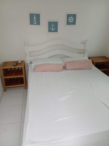 un letto bianco con due cuscini sopra di Excelente casa com Piscina a Camaçari