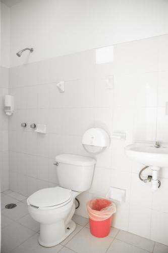 a white bathroom with a toilet and a sink at Hotel Palmarito in Puerto Escondido