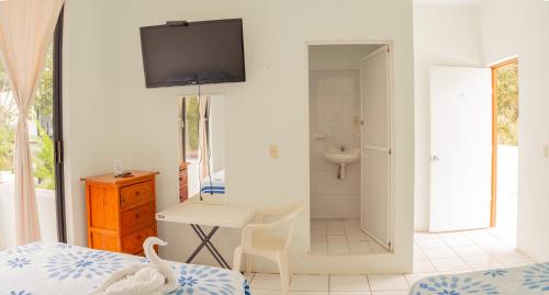 a bedroom with a bed and a bathroom with a tv on the wall at Hotel Palmarito in Puerto Escondido