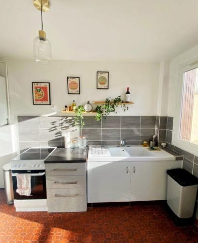 une cuisine blanche avec un évier et une cuisinière dans l'établissement Studio lumineux proche de Paris, à Asnières-sur-Seine