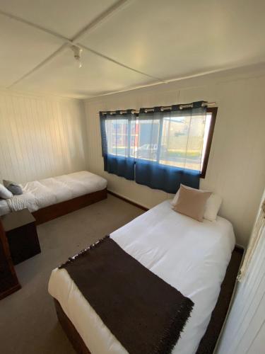 a bedroom with two beds and a window at Hostal Amerindia in Puerto Natales