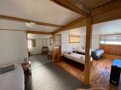 a bedroom with two beds and a living room at Hostal Amerindia in Puerto Natales