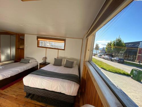 a bedroom with two beds and a large window at Hostal Amerindia in Puerto Natales