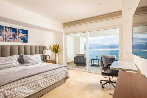 a bedroom with a bed and a desk and a window at Wake Up to Paradise – Stunning 2BR Condo Right on the Beach in Puerto Vallarta