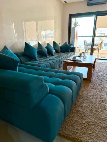 a living room with a blue couch and a table at Fabuleux appartement vue sur mer Fibre IPTV Netflix in Mehdiya-Plage
