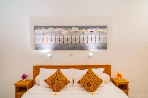 a bed with two pillows and a painting on the wall at Villa Seruni Lovina in Lovina