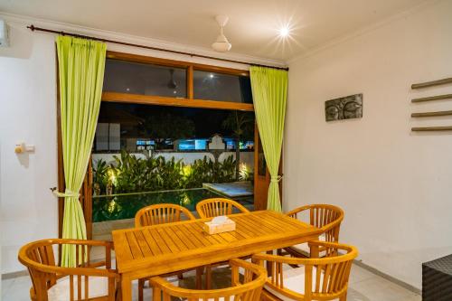 a dining room with a wooden table and chairs at Villa Seruni Lovina in Lovina