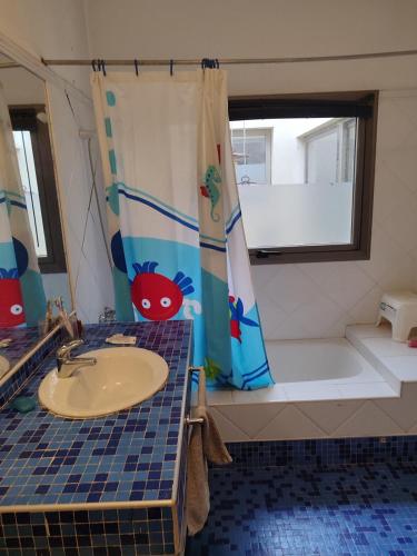 a bathroom with a shower curtain and a sink and a tub at The House you're looking for in Córdoba