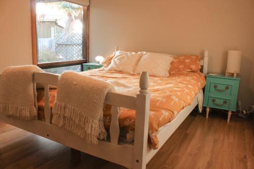 a bed with an orange comforter and a mirror at Sandy Swell Beach Shack - Goolwa in Goolwa South