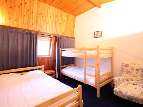 une chambre avec un lit superposé et une chaise dans l'établissement Duplex centre Mont-Dore, 80m², terrasse, parking, 6 pers, no animaux - FR-1-415-130, à Le Mont-Dore