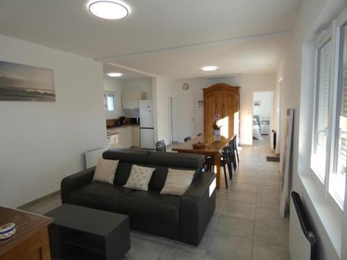 un salon avec un canapé noir et une table dans l'établissement Maison conviviale à 500m de la plage, animaux admis, terrasse et WiFi - FR-1-540-307, à Notre-Dame-de-Monts