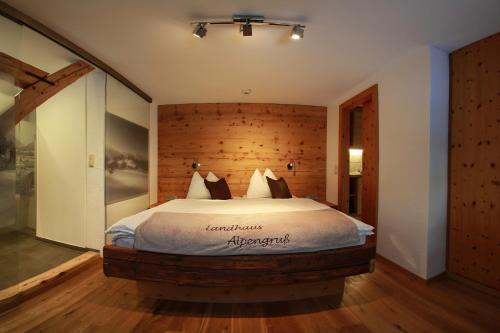 a bedroom with a large bed with a wooden wall at Landhaus Alpengruss in Kössen