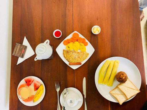 a wooden table with plates of food on it at New Holiday Reach in Unawatuna