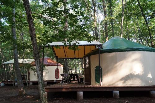 a tent and a table in the woods at PICA Fujiyoshida in Fujiyoshida