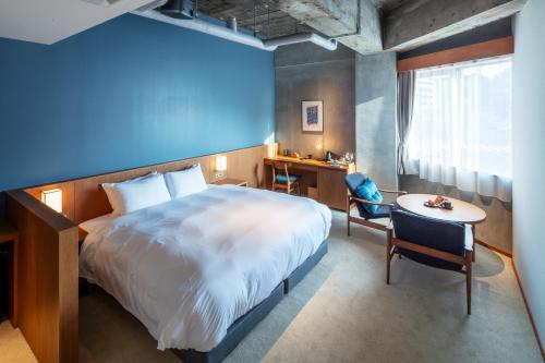 a bedroom with a large bed and a desk and a table at HOTEL AO Kanazawa in Kanazawa