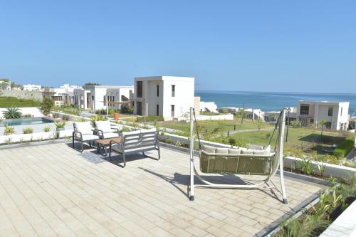 a group of benches on a patio near the ocean at Wateera Jebel Sifah in As Sīfah