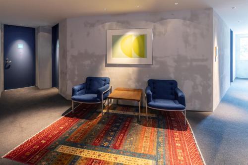 a waiting room with two blue chairs and a table at HOTEL AO Kanazawa in Kanazawa