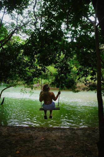a woman sitting on a swing by a river at Aqeel cabin in the nature in Penonomé