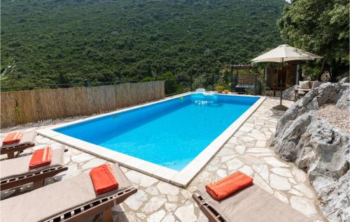 a swimming pool with chairs and an umbrella at Amazing Home In Ploce With Sauna in Ploče