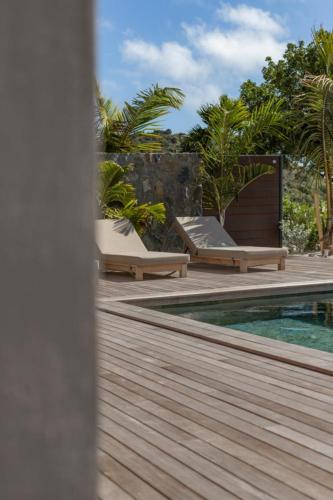a swimming pool with chaise lounges on a wooden deck at 3-bedrooms Villa 5min from Orient Bay in Cul de Sac