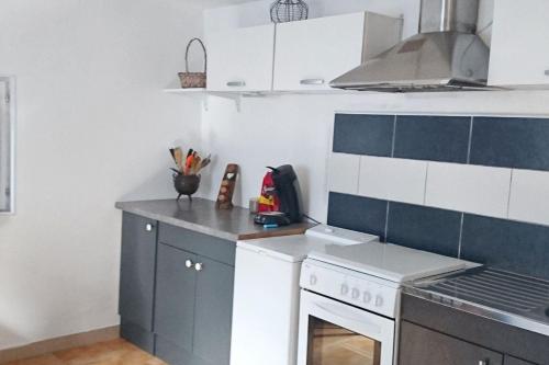 - une cuisine avec des placards bleus et blancs et une cuisinière dans l'établissement Appartement accueillant à Penne-d'Agenais - 32 m² - Terrasse, à Penne-dʼAgenais
