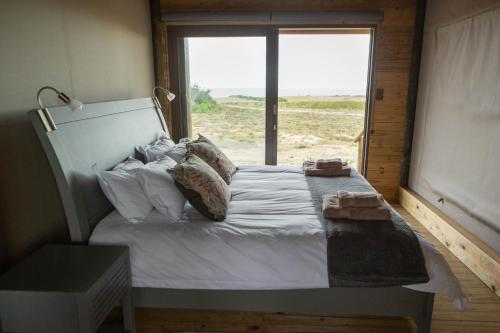 a bedroom with a large bed with a large window at Kuierbos in Gouritzmond