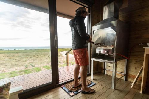 a man cooking food in a stove in a house at Kuierbos in Gouritzmond