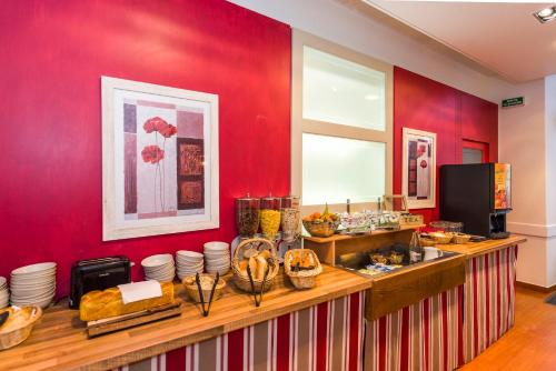 a restaurant with red walls and a counter with food at Hôtel Miléade Le Domaine de la Blairie - Saumur in Saint-Martin-de-la-Place