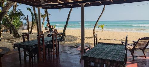 a table and chairs on a beach with the ocean at Haus am Meer "Wilde Ananas" in Koggala
