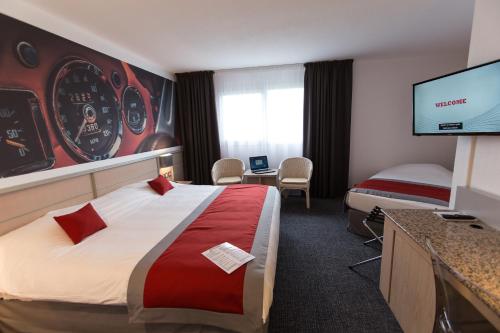 a hotel room with a bed and a flat screen tv at Hotel Le Paddock in Magny-Cours