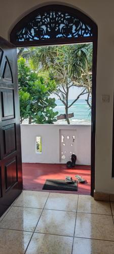 an open door to a room with a view of the ocean at Haus am Meer "Wilde Ananas" in Koggala