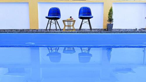 two blue chairs sitting next to a swimming pool at Asapin Vanymahal in Rāmnagar