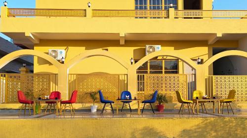 a group of tables and chairs in front of a yellow building at Asapin Vanymahal in Rāmnagar