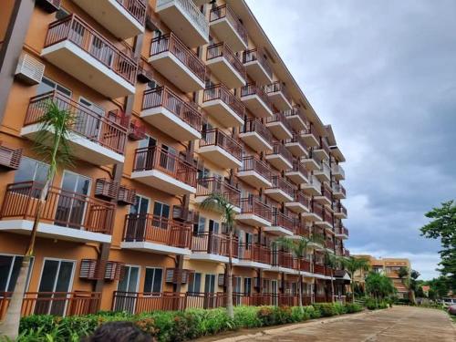 a large apartment building with palm trees in front of it at Cozy and Affordable Deluxe Condo near Puerto Princessa Airport in Puerto Princesa City
