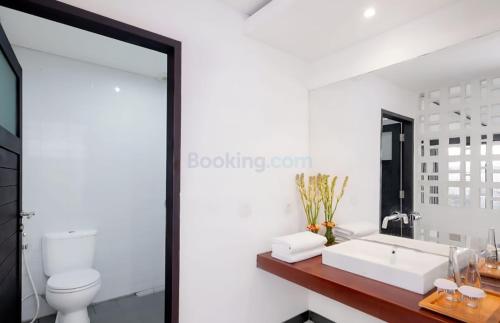 a bathroom with a white sink and a mirror at The Kanjeng Suites Kuta Galeria - Bali in Kuta