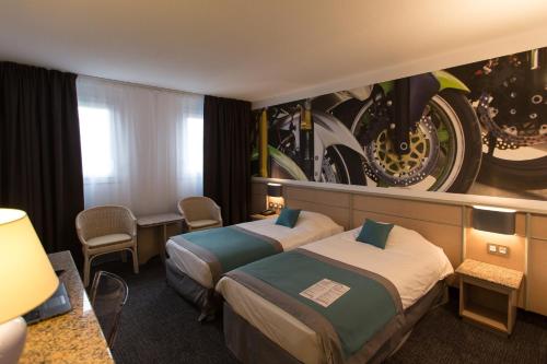 En eller flere senge i et værelse på Hotel Le Paddock