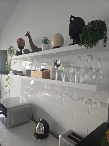 a kitchen with white shelves with glasses and plants at Private Suite Nautilus Beach Front Resort in Coffs Harbour