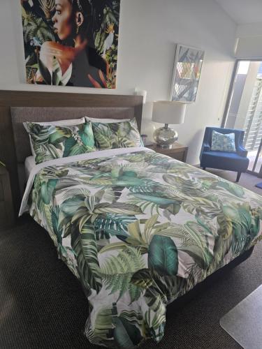 a bedroom with a bed with a green and white comforter at Private Suite Nautilus Beach Front Resort in Coffs Harbour