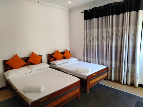 zwei Einzelbetten in einem Zimmer mit Fenster in der Unterkunft Bolagala Nature Resort in Madampella Pahala