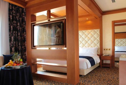 a hotel room with a bed and a flat screen tv at Thousand Nights Hotel Amman - فندق ثاوزند نايتس عمان in Amman