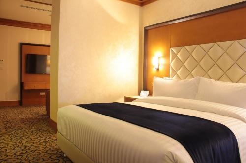 a hotel room with a large bed and a television at Thousand Nights Hotel Amman - فندق ثاوزند نايتس عمان in Amman